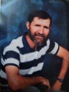 Man smiling with beard wearing striped polo shirt, peaceful pose, professional portrait.