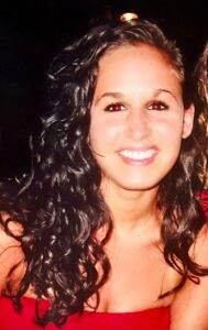 Elegant woman with curly dark hair smiling, representing compassion and care in pet cremation services.