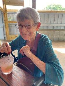 Peaceful elderly woman enjoying drink at outdoor patio, representing comfort and caring funeral services.
