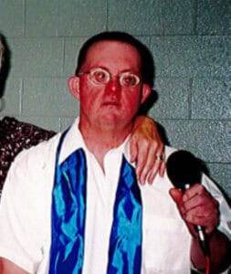 Craig Jones 1. Man with glasses holding microphone at memorial service or funeral event.