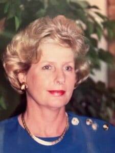 Soft-focused portrait of a woman with styled hair, elegant jewelry, and a blue outfit, representing compassionate cremation services.