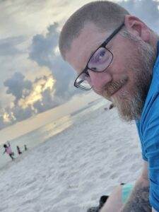 Serene beach scene with a smiling man enjoying sunset, showcasing comfort and peace during difficult times.