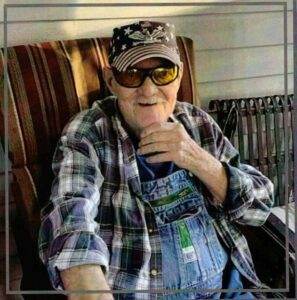 Gentle senior man smiling with sunglasses, wearing plaid shirt, sitting outdoors, symbolizing comfort during cremation services.