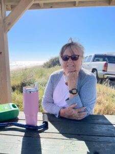 Gentle coastal scene with a smiling elderly woman enjoying a day outdoors at Dogwood Cremations LLC.